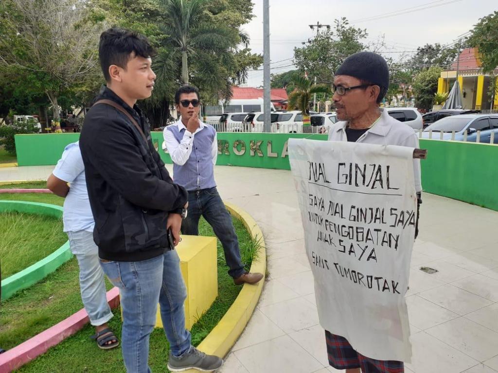 Eli Kristianto saat memajang tulisan hendak menjual ginjal di parkiran pelabuhan Karimun. ILHAM