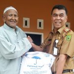 Sekdakab Natuna, Wan Siswandi menyerahkan beras CPP kepada masyarakat. (fatur/haluankepri.com)