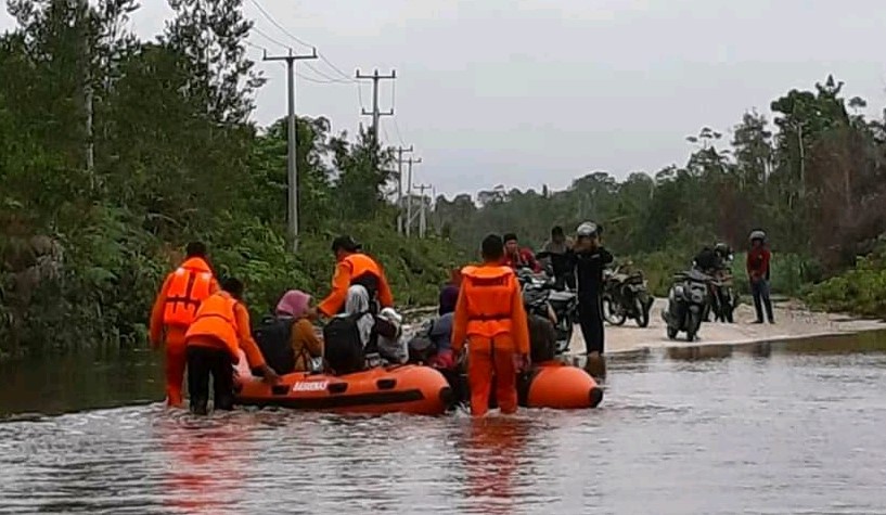 Petugas dari Sarnas dan aparat lainnya membantu warga melintasi jalan yang terkena banjir. (fatur/haluankepri.com)