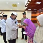 Bupati Karimun, Aunur Rafiq, menyerahkan zakat kepada Mustahik di Aula Masjid Agung Karimun, Selasa (24/12/2019). (ilham/haluankepri.com)