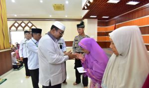 Bupati Karimun, Aunur Rafiq, menyerahkan zakat kepada Mustahik di Aula Masjid Agung Karimun, Selasa (24/12/2019). (ilham/haluankepri.com)