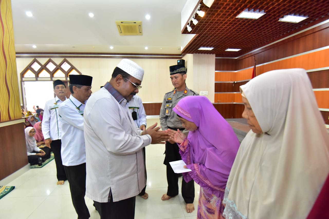 Bupati Karimun, Aunur Rafiq, menyerahkan zakat kepada Mustahik di Aula Masjid Agung Karimun, Selasa (24/12/2019). (ilham/haluankepri.com)